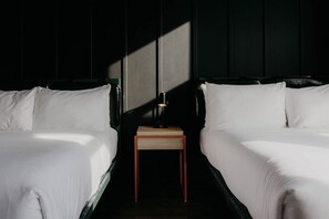 Une chambre d’hôtel avec deux lits, une petite table de chevet en bois et une lampe.