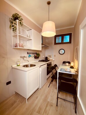 A compact kitchen with white cabinetry, a sink, a stove, and a dining area with a table and chairs.