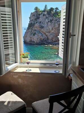 Habitación con vista a una costa rocosa y al mar. Hay dos copas de vino sobre un alféizar.