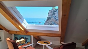 Habitación con vista al mar y acantilados, con una pequeña mesa y dos sillas.