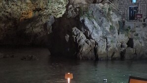 Mesa y sillas junto a un cuerpo de agua con un paisaje rocoso de fondo.