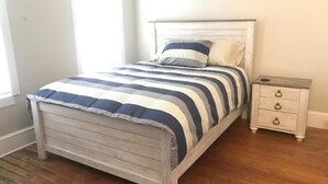 A bed with a striped bedspread, a wooden headboard, and a nightstand with drawers.