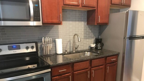 A kitchen with a stainless steel refrigerator, a microwave, an oven, and wooden cabinets.