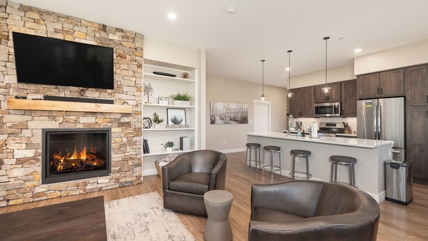 Una sala de estar moderna con chimenea de piedra, sofás de cuero y televisor de pantalla plana.