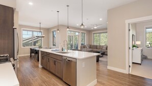 Una cocina moderna con una isla central, armarios de madera y un comedor con sillas.