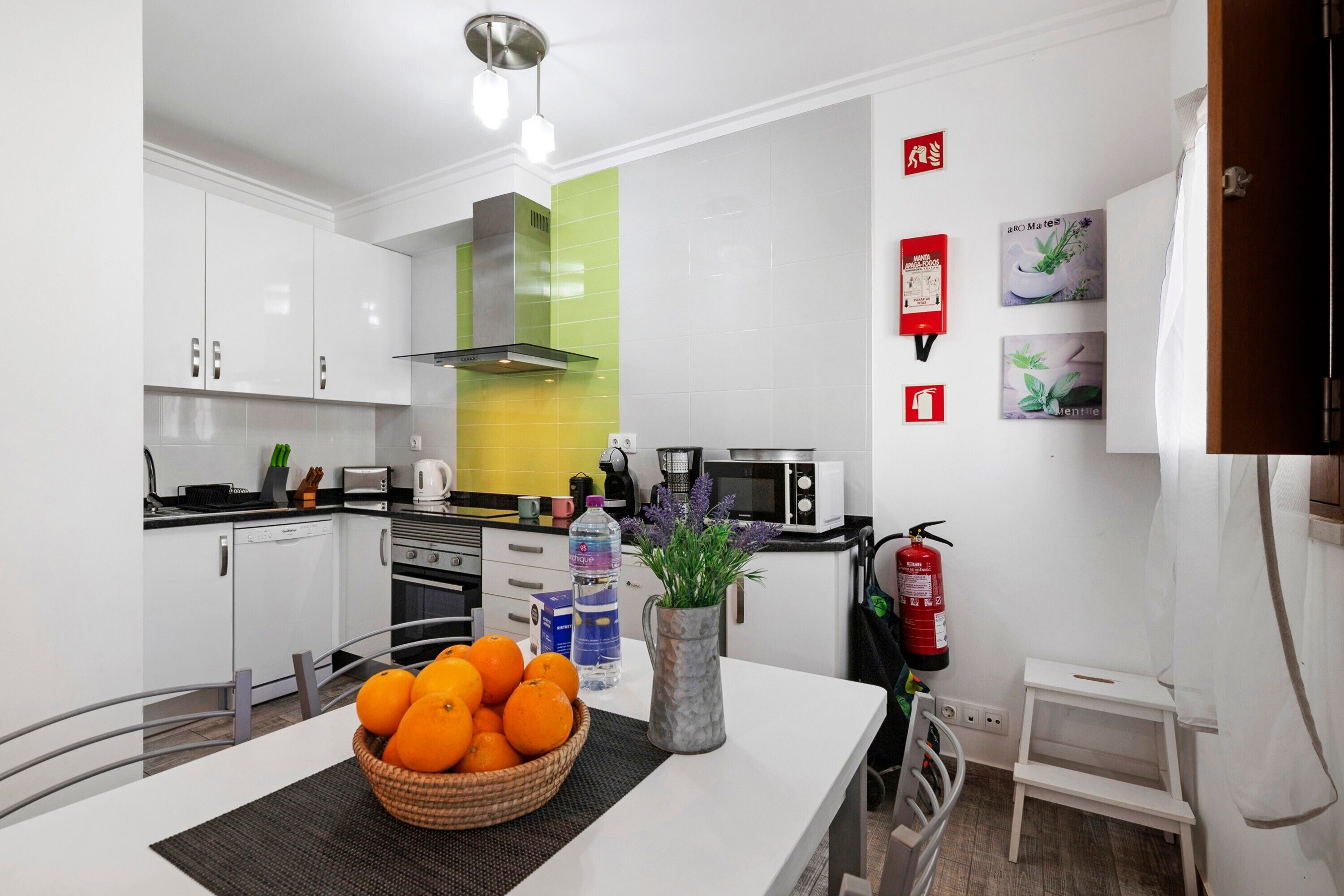 A modern kitchen with white cabinets, a microwave, a toaster, and a fire extinguisher on the wall.