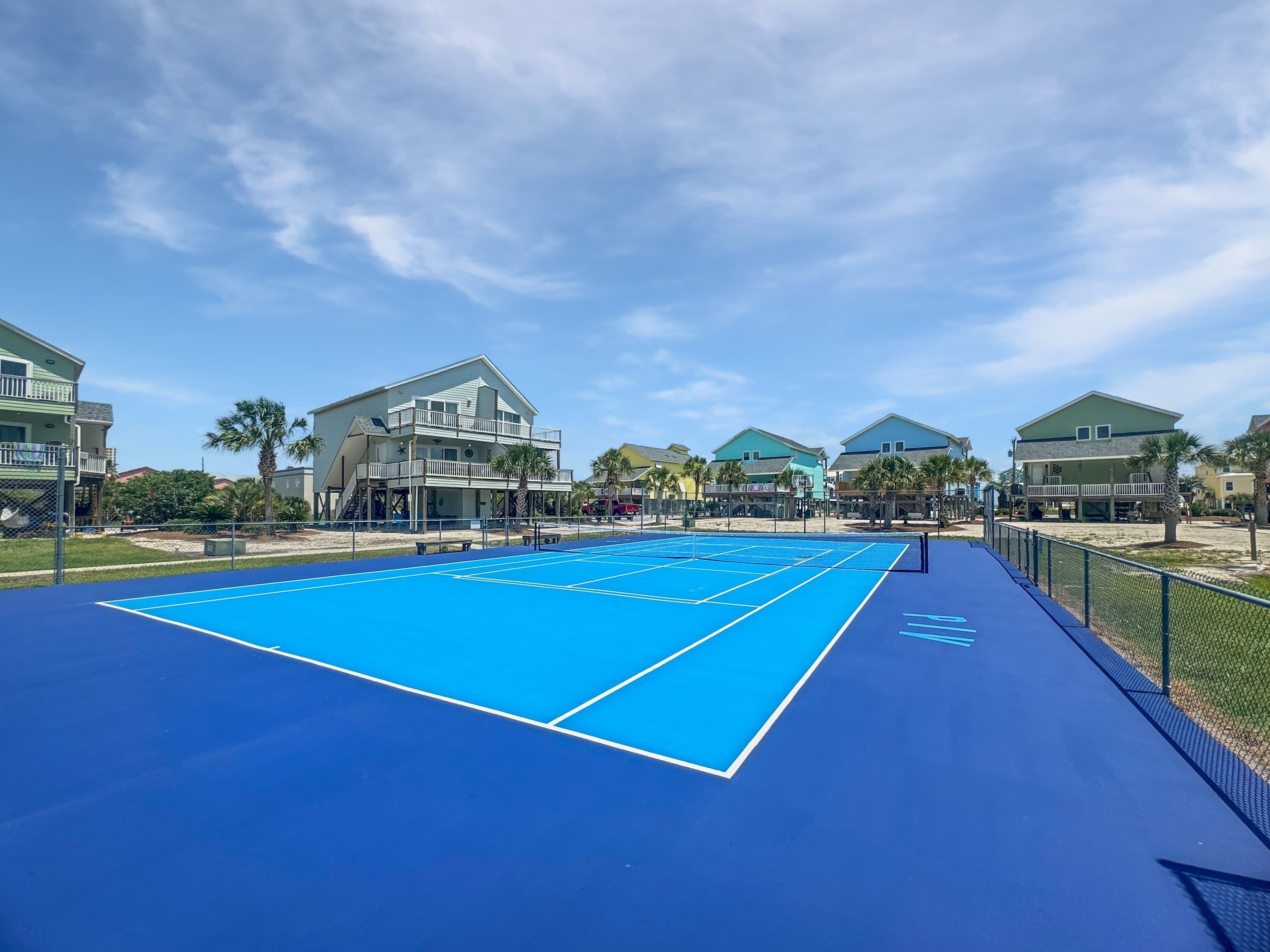 Un court de tennis extérieur bleu, entouré de maisons dotées de balcons.