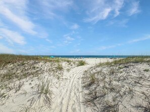 Una spiaggia con dune di sabbia e cielo sereno.