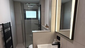 Een moderne badkamer met een wit wastafelmeubel, een spiegel en een handdoekrek.