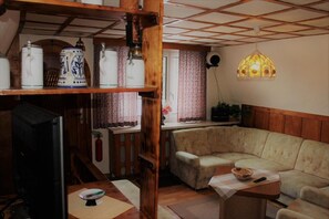 A cozy living room with a sofa, a television, and a wooden shelf with decorative items.