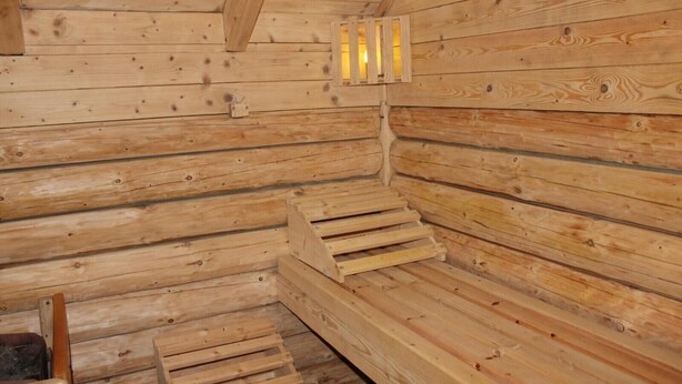 L’intérieur d’une cabane en rondins, avec des murs en bois, un banc et une petite fenêtre.