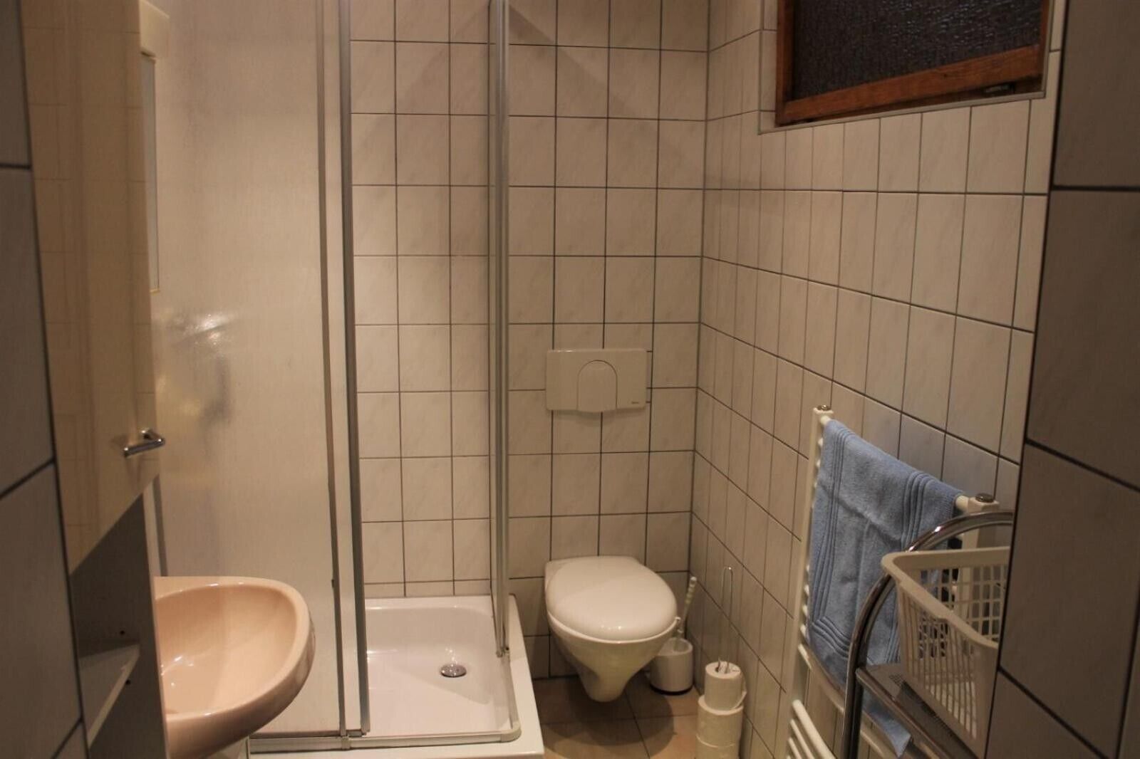 Un baño con ducha, inodoro, lavabo y toallero.