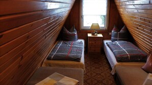 Une chambre de style cabane avec deux lits, une petite table avec une lampe et une fenêtre.