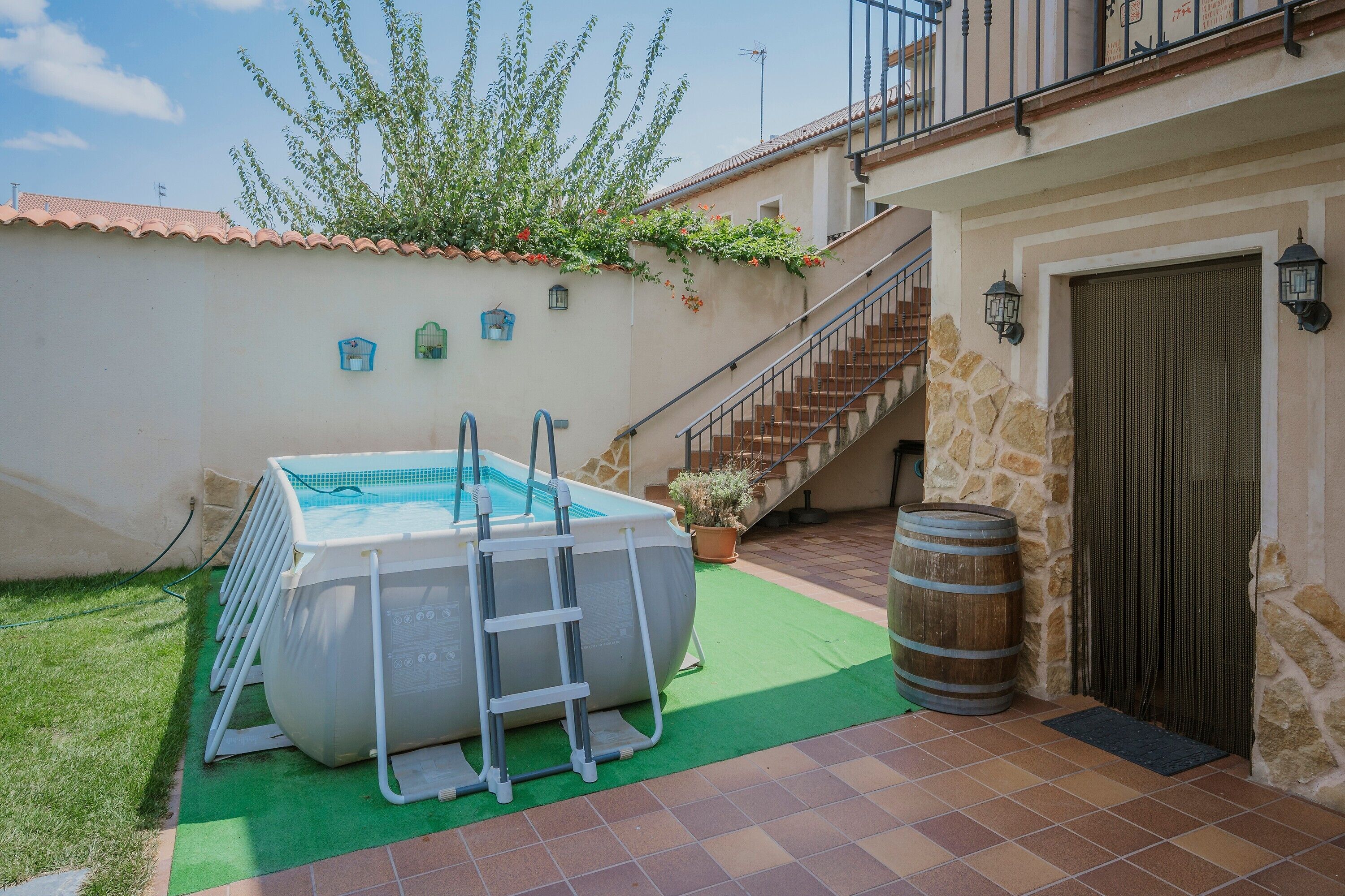 Une piscine avec un échelle, un mur en pierre, un escalier et une porte surmontée d’une lanterne.