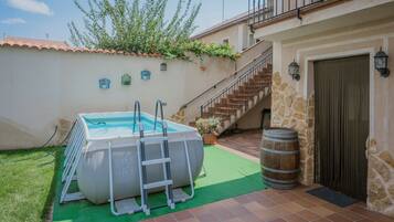 Une piscine avec un échelle, un mur en pierre, un escalier et une porte surmontée d’une lanterne.