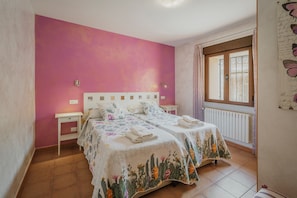 Une chambre avec deux lits, une fenêtre avec des rideaux, un radiateur et un mur décoré avec des motifs de papillons.