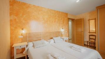 A hotel room with two beds, a wooden headboard, a nightstand, a chair, and a mirror.