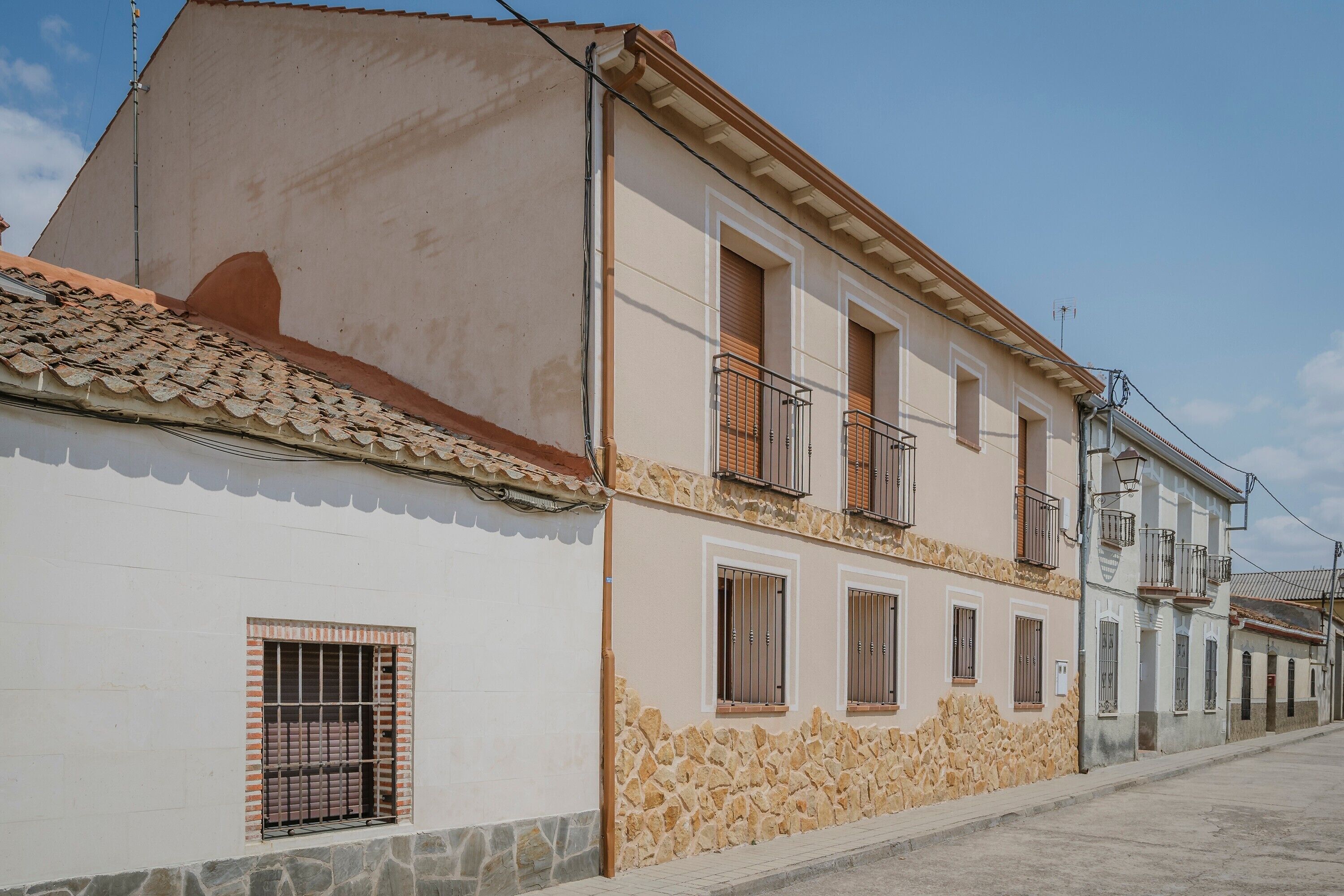 Un edificio de dos pisos con base de piedra, varias ventanas y tejado de tejas.