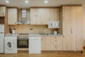 Une cuisine dotée de meubles en bois, d’une hotte de cuisinière en acier inoxydable, d’un four à micro-ondes encastré, d’un lave-vaisselle et d’un plan de travail en granit.