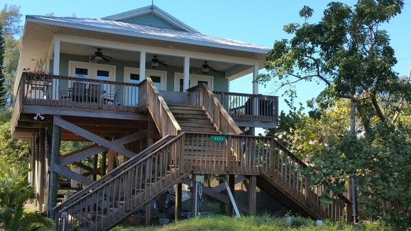 A two-story house with a wooden deck and a staircase leading to the upper floor.
