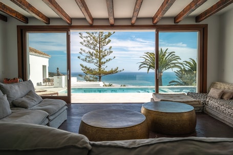 A spacious living room with a large sliding glass door leading to a pool and ocean view.