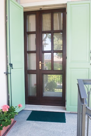 A wooden door with glass panels, a green door frame, and a green mat at the entrance.