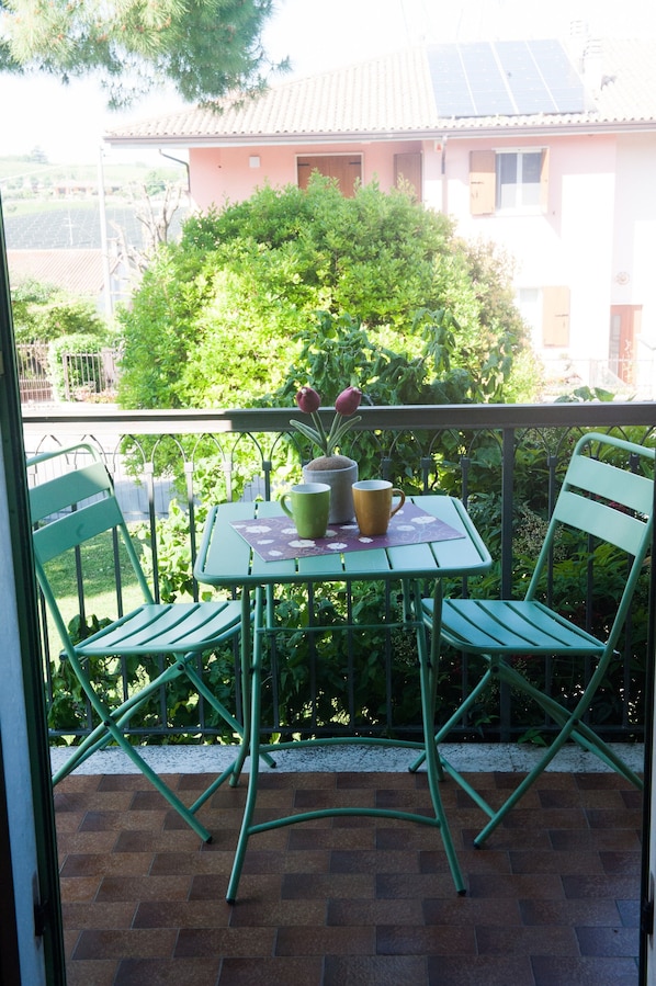 A balcony with a table, chairs, and a potted plant.