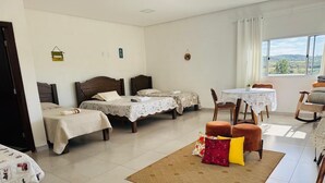 A hotel room with three beds, a dining table, and a view of the outdoors. - Pousada Dona Terezinha (Formiga)