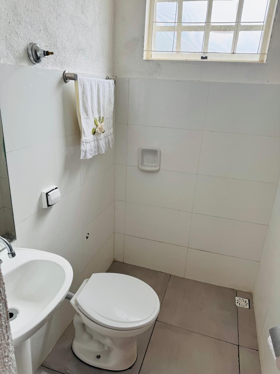 A small, clean bathroom with a toilet, sink, and a window.
