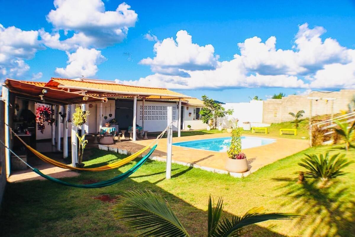 Une maison avec une piscine, un hamac et un espace patio.