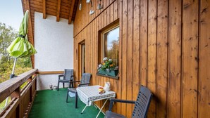 Une terrasse en bois avec une table, des chaises et un parasol vert.