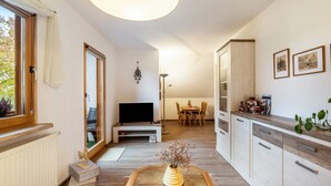 Un salon moderne doté d’un téléviseur, d’un coin repas et d’une cuisine avec des meubles en bois.