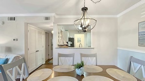 A dining area with a wooden table, four chairs, and a hanging light fixture.