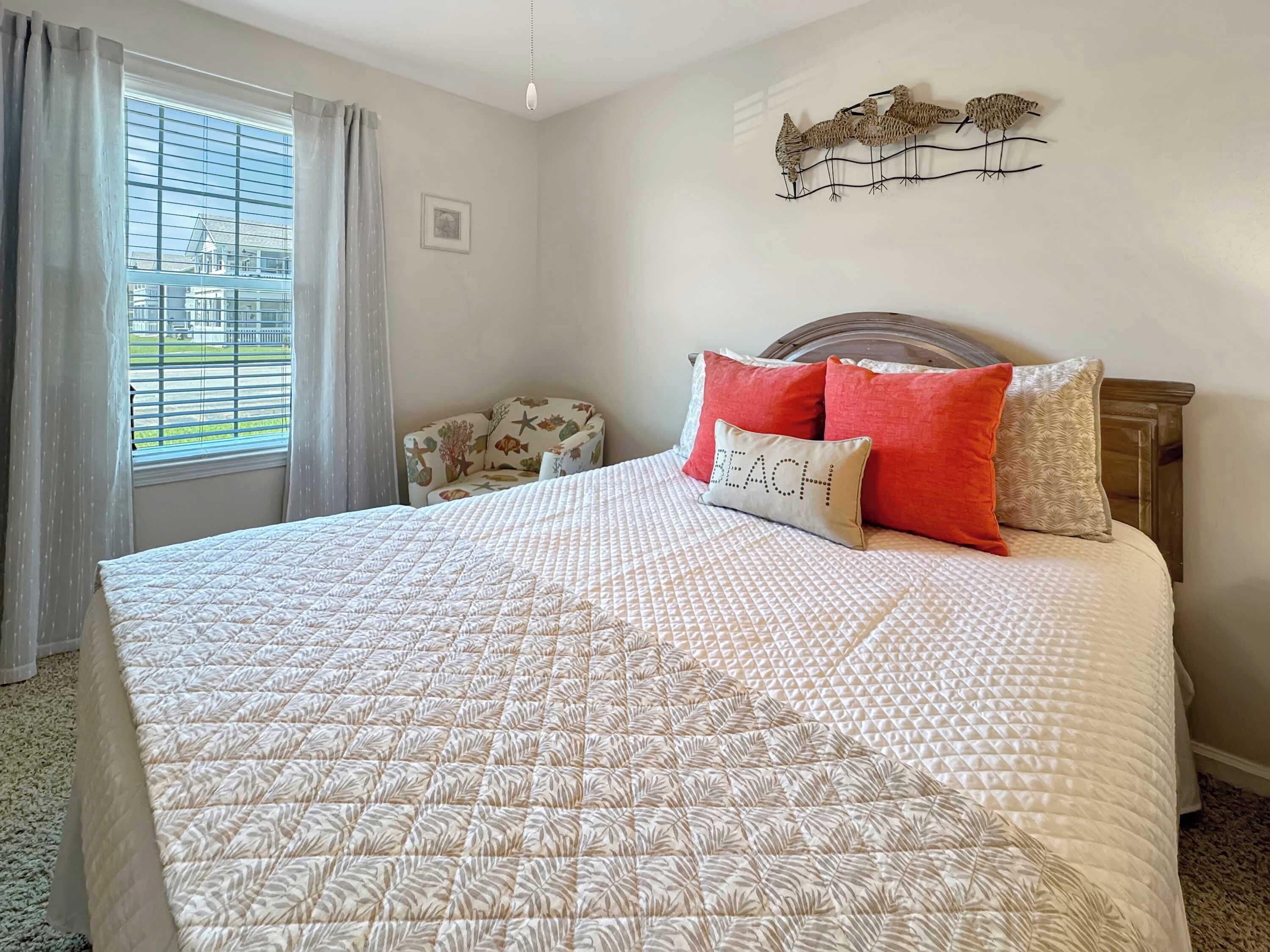Un dormitorio con una cama grande, cabecera de madera y vistas al exterior a través de una ventana con cortinas.
