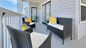 A covered outdoor seating area with wicker furniture and potted plants.