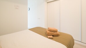Una camera da letto con un letto, una testiera in legno, un armadio con ante scorrevoli e una sveglia a parete.