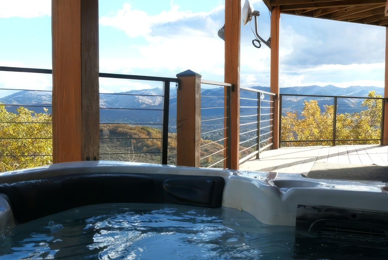 A hot tub with a view of mountains and autumn foliage.