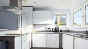 A modern kitchen with white cabinets, a wooden countertop, and a window providing natural light. - Pass the Keys |Modern 2bed Apartment Edinburgh (Edinburgh)