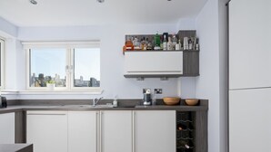 A modern kitchen with white cabinets, a built-in wine rack, and a window with a city view. - Pass the Keys |Modern 2bed Apartment Edinburgh (Edinburgh)
