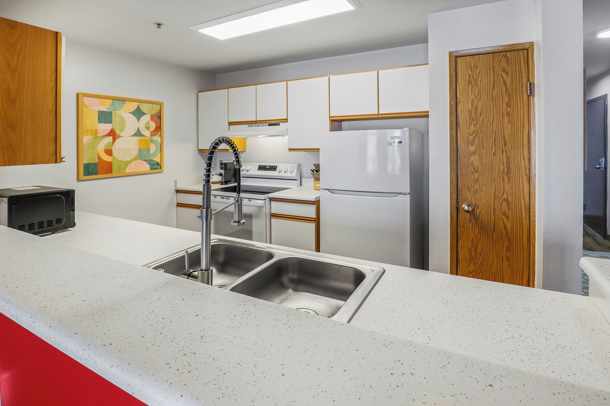 A modern kitchen with white cabinetry, stainless steel appliances, and a double sink.
