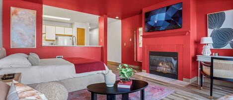 A modern living room with a fireplace, a sofa, a coffee table, and a dining area with a lamp.