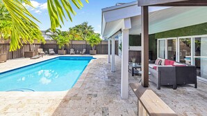 Un jardin avec une piscine, des meubles de patio et un espace salon abrité.