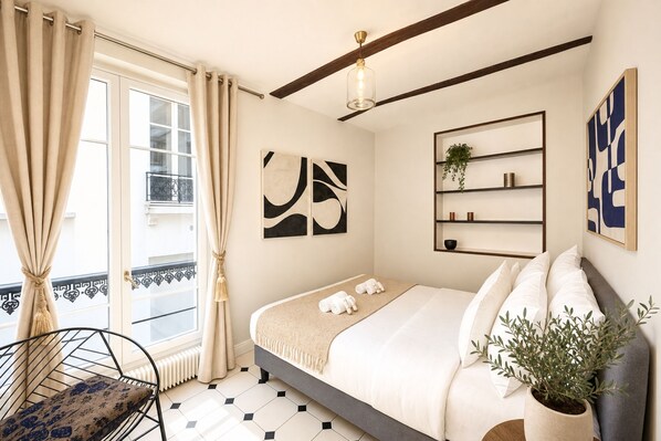 Un dormitorio con cama, una silla, una planta y obras de arte en las paredes.