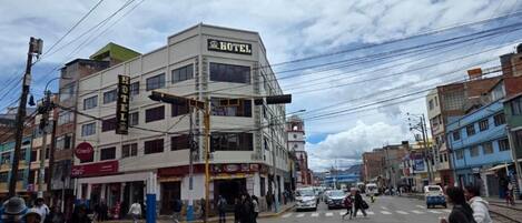 A hotel with multiple floors, a prominent sign, and a street view with pedestrians and vehicles.