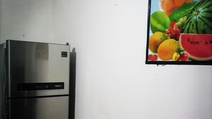 A kitchen with a stainless steel refrigerator and a wall-mounted fruit painting.