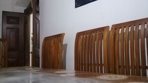 A dining area with a wooden table and chairs, a patterned table runner, and a wall-mounted fruit basket.