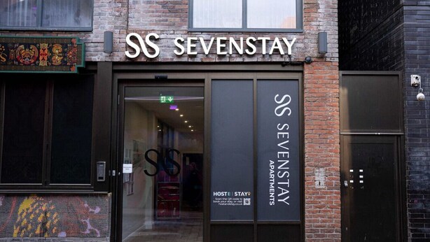 L’entrée d’un hôtel, avec une grande enseigne indiquant : « SOS SEVENSTAY APARTMENTS ».