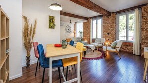 A dining area with a wooden table, colorful chairs, and a vase of pampas grass. - Gambetta Apartment – Right in the Heart of Gaillac (Gaillac)