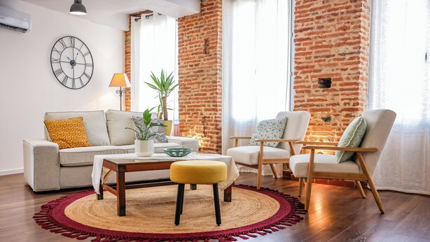A living room with a sofa, armchair, coffee table, and a round rug. - Gambetta Apartment – Right in the Heart of Gaillac (Gaillac)