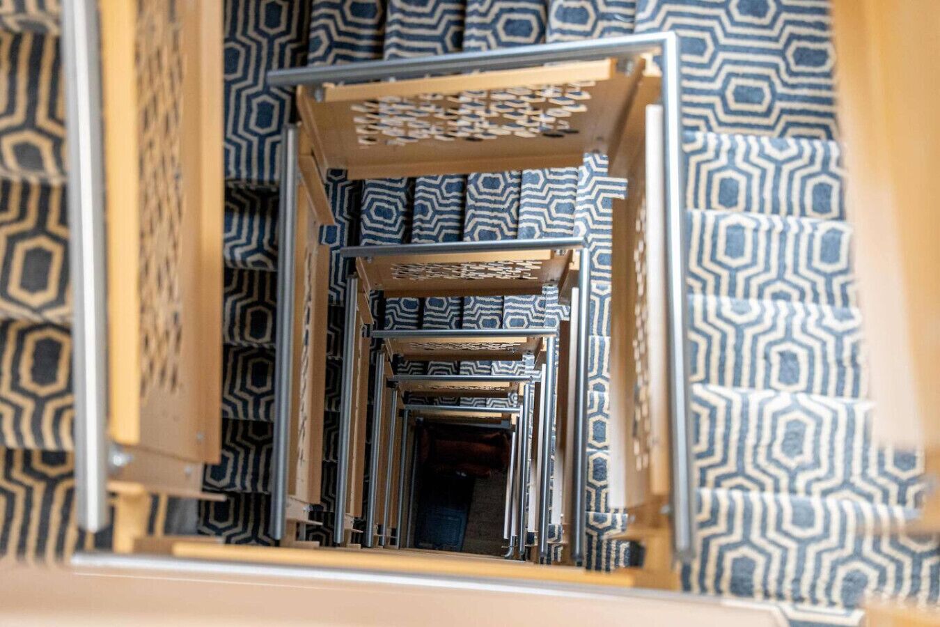 A narrow, patterned hallway with a series of doorways leading into a room.